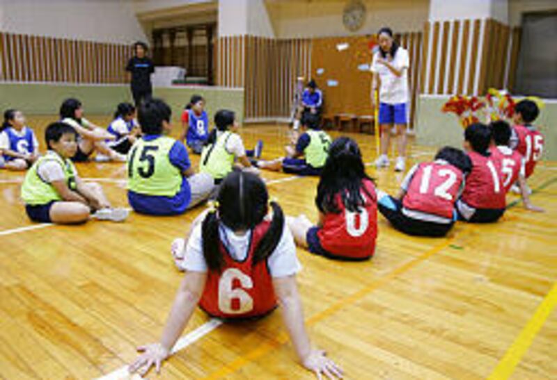 Sayaka Oyama, clad in bib No. 6, joins others to listen to their instructor, Junko Sano, during a sports program for overweight kids in Tokyo.