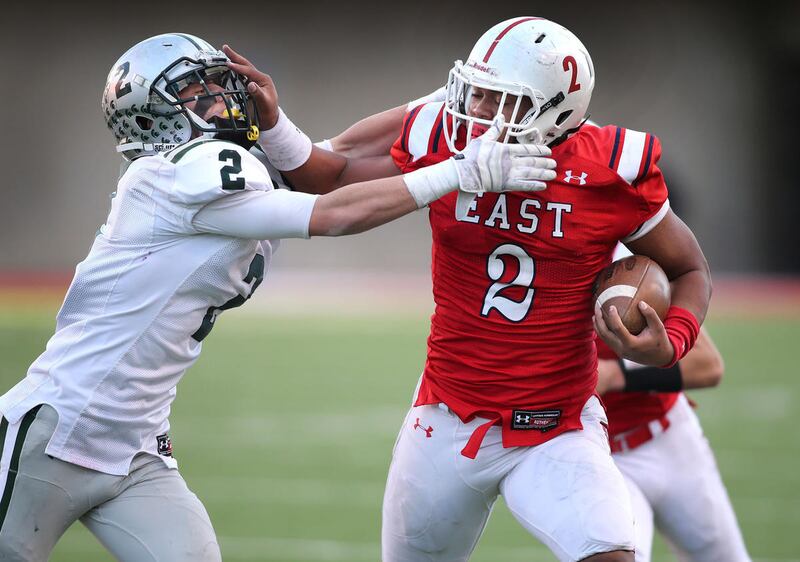 East High's Ula Tolutau stiff arms Olympus' Conner Haller as East High School defeats Olympus High School 47-21in the 4A State High School football semi-final Thursday, Nov. 14, 2013, in Salt Lake City.