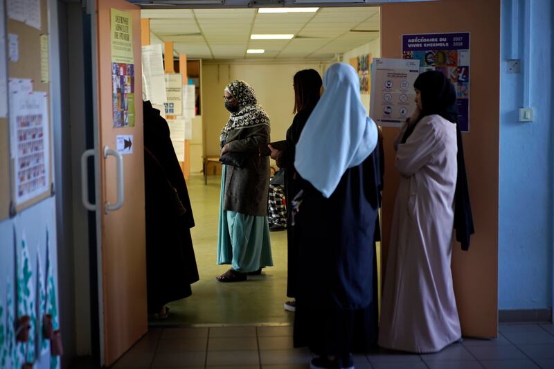 Women wait in line before voting for the first round of the presidential election at a polling station in the Malpasse northern district of Marseille, southern France.