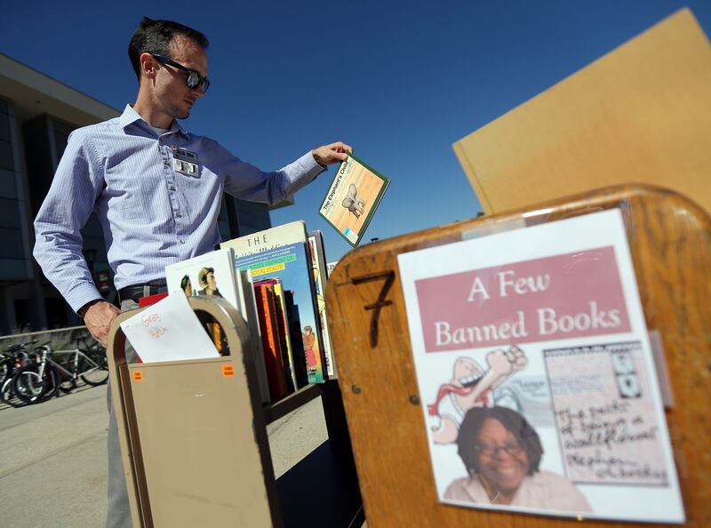 TJ Ferrill looks at previously banned books during a Banned Books Open Reading outside of the Marriott Library.