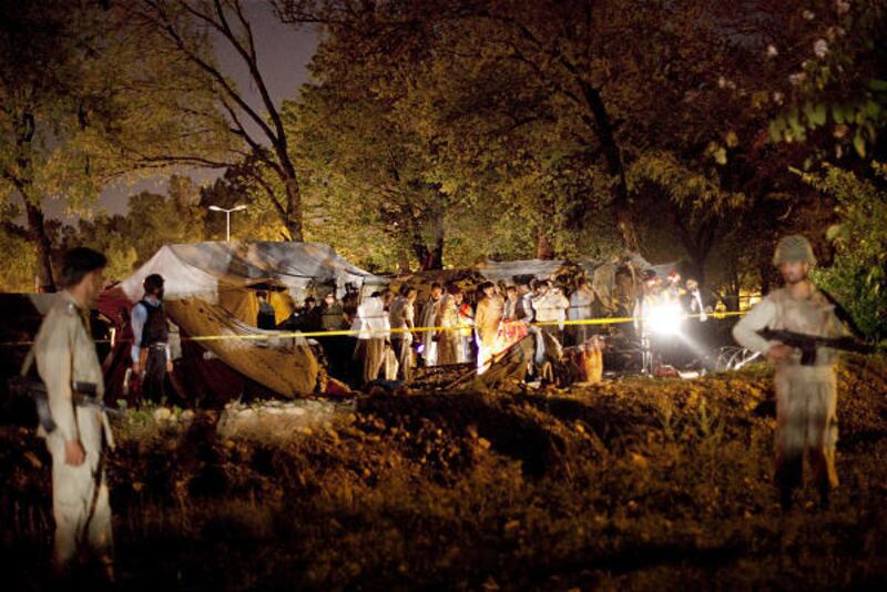 Pakistani paramilitary soldiers stand guard as rescue workers collect evidence at the area of a suicide bombing that killed eight in Islamabad.