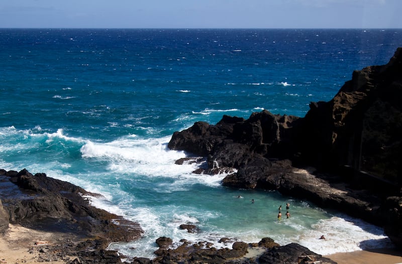 People swim in an alcove as waves crash along the southeast coast of O’ahu near Kalaniana’ole Highway in Honolulu, Hawaii.
