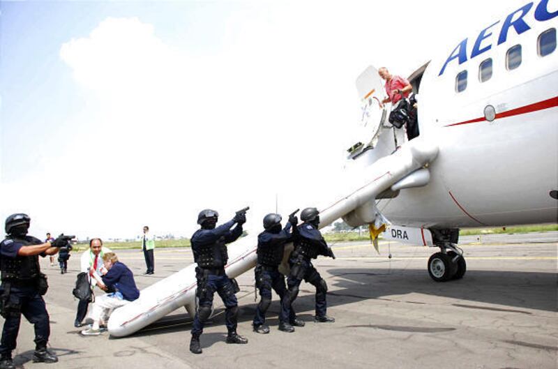 Police officials stand guard as passengers leave a hijacked plane at the airport in Mexico City Wednesday.