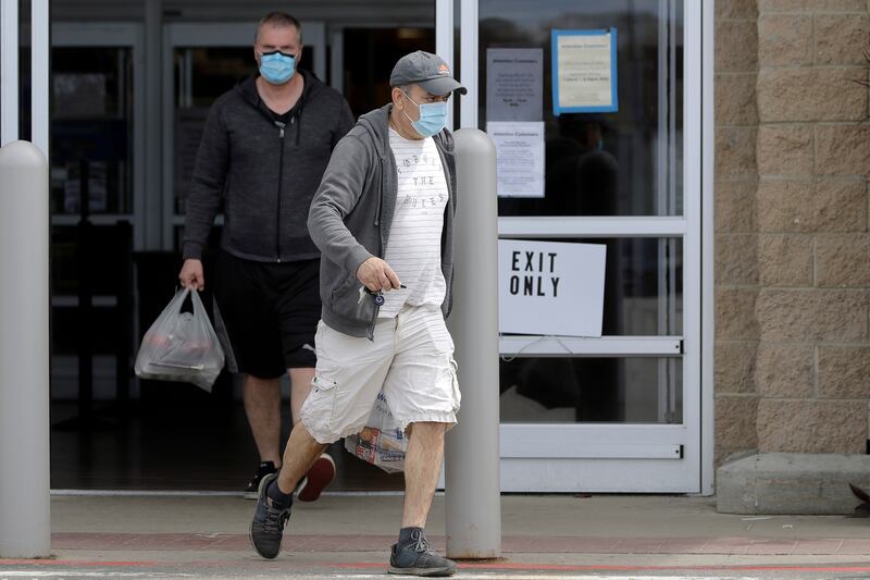 Men wearing protective masks during the coronavirus pandemic exit a Walmart, Wednesday, May 6, 2020, in Walpole, Mass. An executive order signed the previous week by Gov. Charlie Baker took effect Wednesday mandating the use of masks when individuals are not able to socially distance themselves from others.