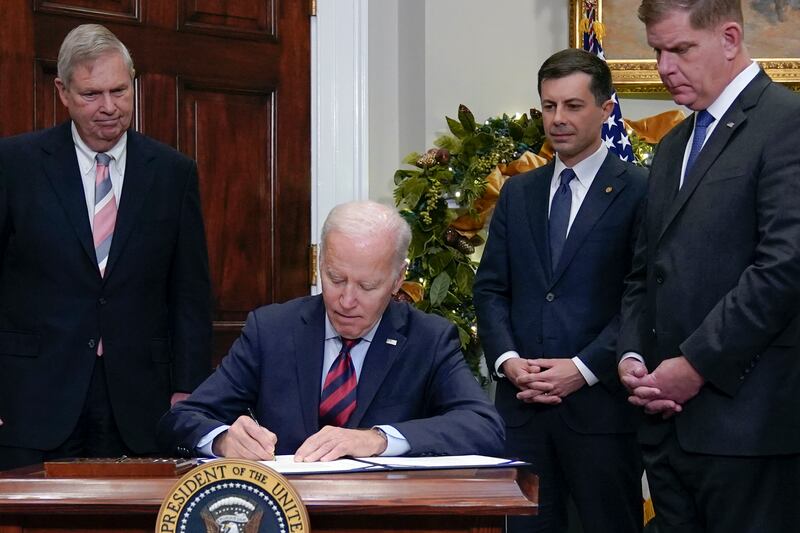 President Joe Biden on Friday, Dec. 2, 2022, signs a bill at the White House that aims to avert a freight rail strike.