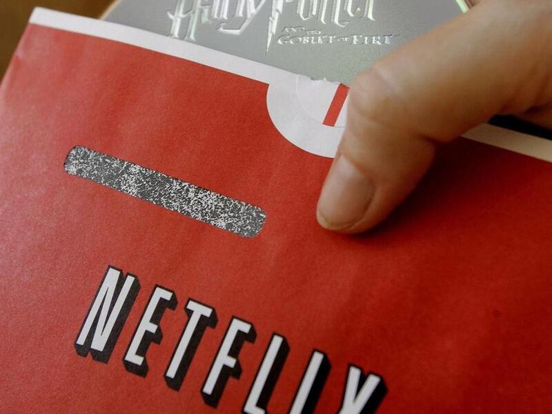 FILE - In this July 21, 2006 file photo, Netflix customer Victoria Tichenor poses with a Netflix envelope and a DVD in Palo Alto, Calif. Netflix on Tuesday, July 12, 2011 said it is raising its prices by as much as 60 percent for millions of subscribers