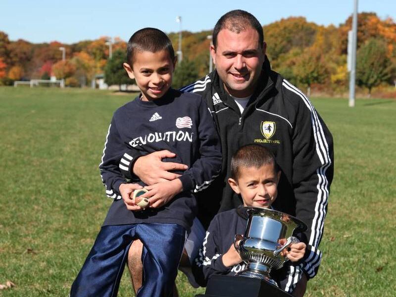 Darius Shirzadi and his two boys, Ariel, 10, and Adrian, 9, hold a soccer cup from a recent game. Shirzadi founded Project GOAL, a nonprofit program comprised of sports professionals with one goal in mind: helping disadvantaged youth through soccer-relate