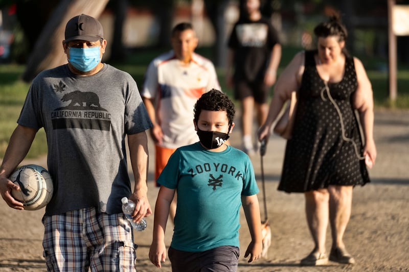 In this May 9, 2020, file photo, adults and children wearing masks amid the coronavirus pandemic exercise around a track at the Van Nuys/Sherman Oaks Recreation Center, in the Sherman Oaks section of Los Angeles.