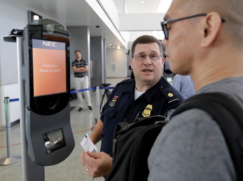 U.S. Customs and Border Protection supervisor Erik Gordon, center, helps a passenger navigate one of the new facial recognition kiosks at a United Airlines gate before boarding a flight to Tokyo, Wednesday, July 12, 2017, at George Bush Intercontinental A