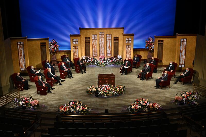 Members of the First Presidency and Quorum of the Twelve Apostles are seen sitting before a session of general conference.