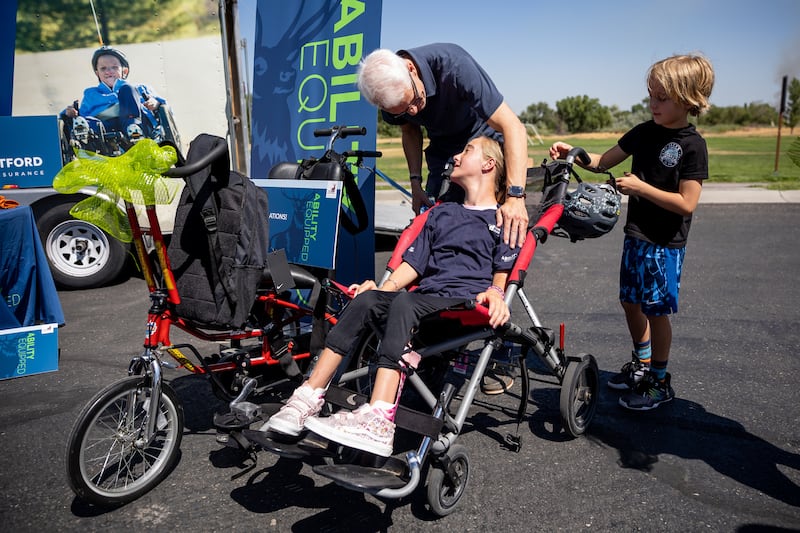 Audrey Sterner, 13, looks up at her father, Josh Sterner, after receiving a new adaptive tricycle at Germania Park in Murray.