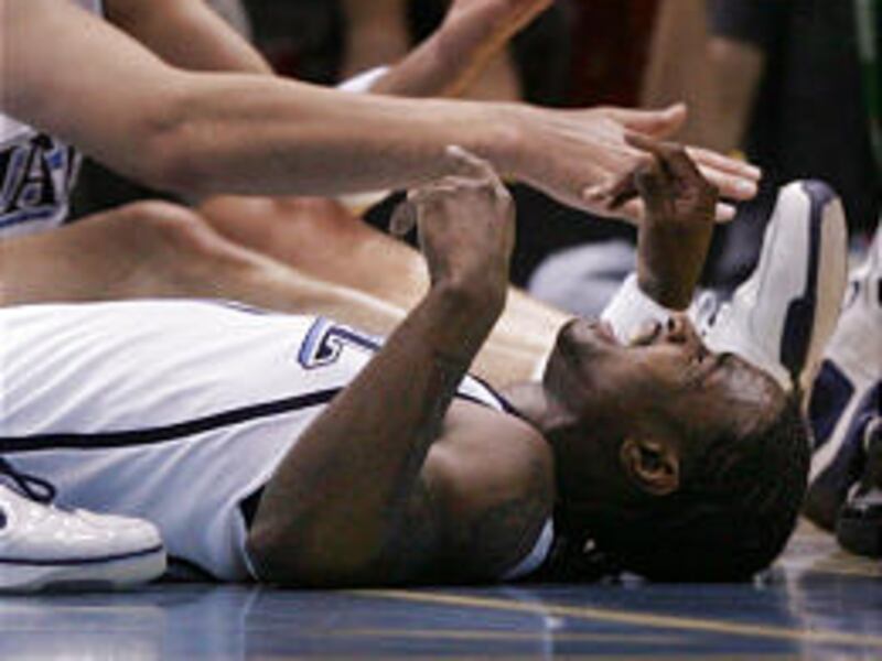 Utah's Dee Brown winces in pain after being fallen on by teammate Mehmet Okur, back, Wednesday night against Golden State.