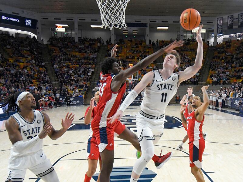 Utah State guard Max Shulga (11) shoots as Fresno State center Eduardo Andre defends during the second half of an NCAA college basketball game Saturday, Dec. 31, 2022, in Logan, Utah.