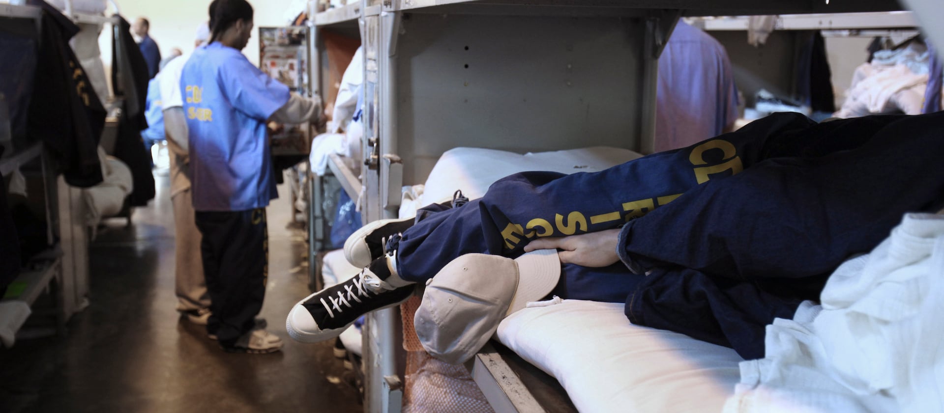 An inmate in a California prison lays on a triple-tier bunk in a gymnasium converted to house prisoners at the California Substance Abuse Treatment Facility and State Prison.