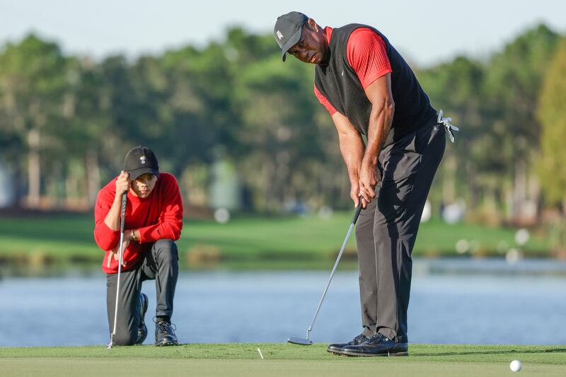 Charlie Woods watches his father Tiger Woods putt in Dec. 2022.
