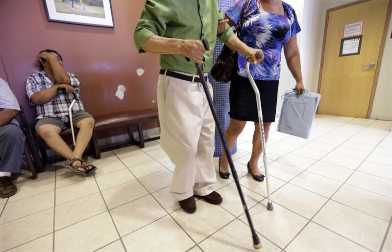 In this July 12, 2012 photo, a man using two canes is helped in the waiting area at Nuestra Clinica Del Valle in San Juan, Texas. About 85 percent of those served at the clinic are uninsured. Texas already has one of the nationÕs most restrictive Medicaid