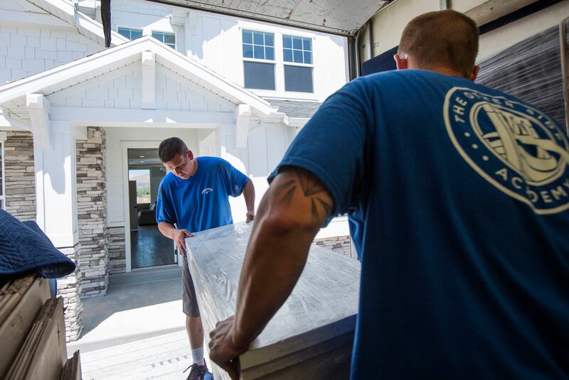 Ryan Chidester, left, and Eric Morgan, residents of The Other Side Academy, move a dresser into the Darling family's newly constructed home in Lehi on Tuesday, July 18, 2017.