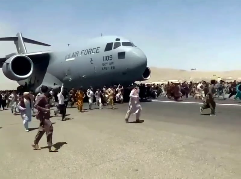 Fleeing Afghan people run alongside a U.S. Air Force jet at an airport in Kabul, Afghanistan.