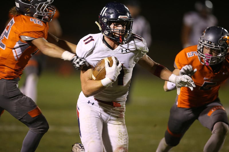 Springville's 11 Cole Bowers runs past Skyridge's 42 Jaxon Peck and 5 Garrett Rusick during the second half at Skyridge High School in Lehi on Friday, Oct. 6, 2017.