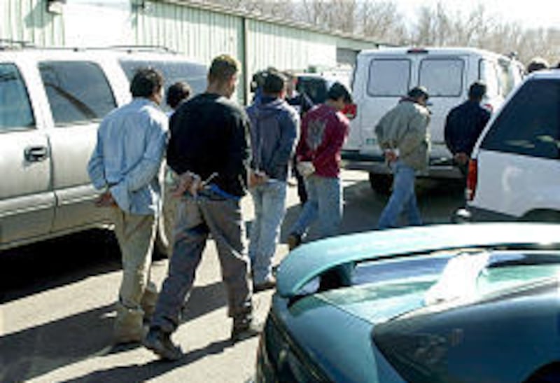 Workers at Champion Safe are taken away in handcuffs after INS raided the business in February 2003.