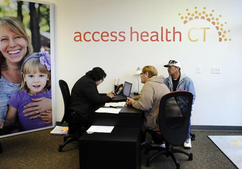 Gildred Ortiz, center and Julio Colon, right, receive help from outreach worker for Access Health CT, Cristela Solorio Ruiz during a grand opening for Connecticut's health insurance exchange's first insurance store, Thursday, Nov. 7, 2013, in New Britain,