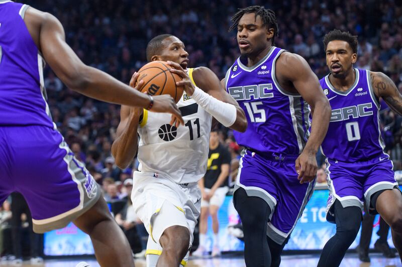 Utah Jazz guard Kris Dunn (wearing white) drives to the basket past Sacramento Kings guard Davion Mitchell (15) and guard Malik Monk (0).