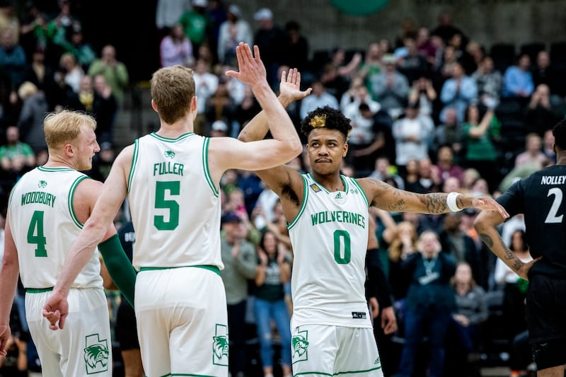 Utah Valley guard Justin Harmon (0) high-fives teammate Tim Fuller (5) while Trey Woodbury (4) looks on during the Wolverines’ win in the NIT quarterfinals.