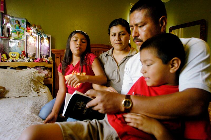 In this May 13, 2004, file photo, Jose Aguilar, and his wife, Maria, read a book with their children Jose Jr.,7, and Jennifer, 9, at their home in National City, Calif. The Aguilar children are U.S. citizens by virtue of their American birth, but their pa