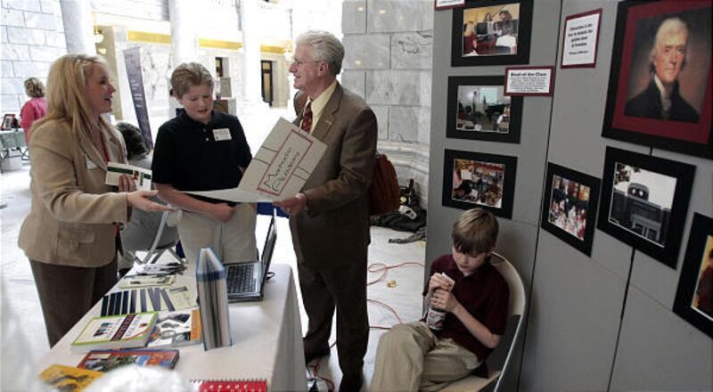 Kristy Smith, left, and her sons Andrew and Bryan talk with Rep. Don Ipson, R-St. George, as the family runs an informational booth for Monticello Academy at the state Capitol on Thursday. Utah has 67 charter schools up and running.