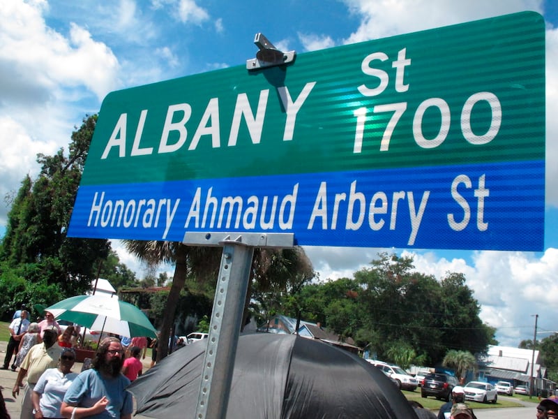 A crowd gathers under a new sign designating a city roadway as Honorary Ahmaud Arbery Street in Brunswick, Ga
