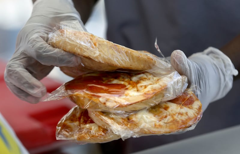 Nutrition technician Besie Sabit puts slices of pizza into bagged lunches outside of Edison Elementary School.