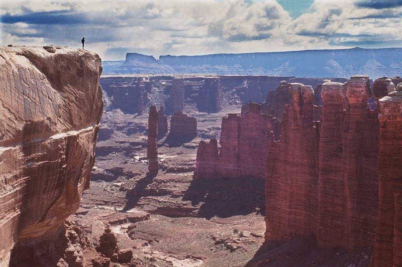 A hiker looks down at the White Rim Trail in Canyonlands National Park.