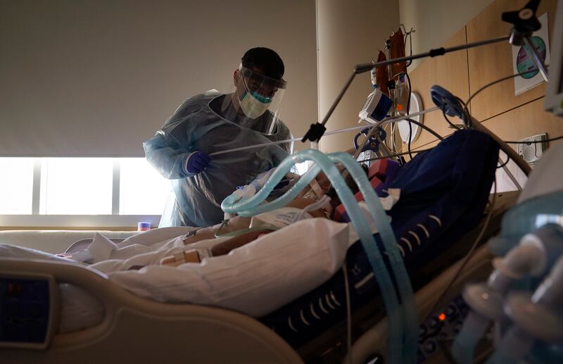 In this Dec. 22, 2020, file photo, Dr. Mher Onanyan tends to a COVID-19 patient at Providence Holy Cross Medical Center in the Mission Hills section of Los Angeles. In hard-hit Los Angeles County, the total COVID-19 death toll has reached 10,850 and confirmed cases topped 818,000 on Monday, Jan. 4, 2021.