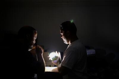 Jorge M. Alvarado, right, shows a solar powered light to his brother, Miguel Angel Alvarado, at his home in Bayamón, Puerto Rico, on Friday, Dec. 8, 2017.