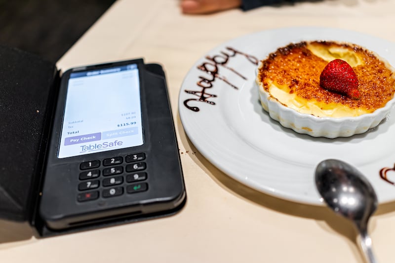 A table at Fogo de Chao Brazilian steakhouse with a TableSafe brand digital payment system by a creme brulee dessert.