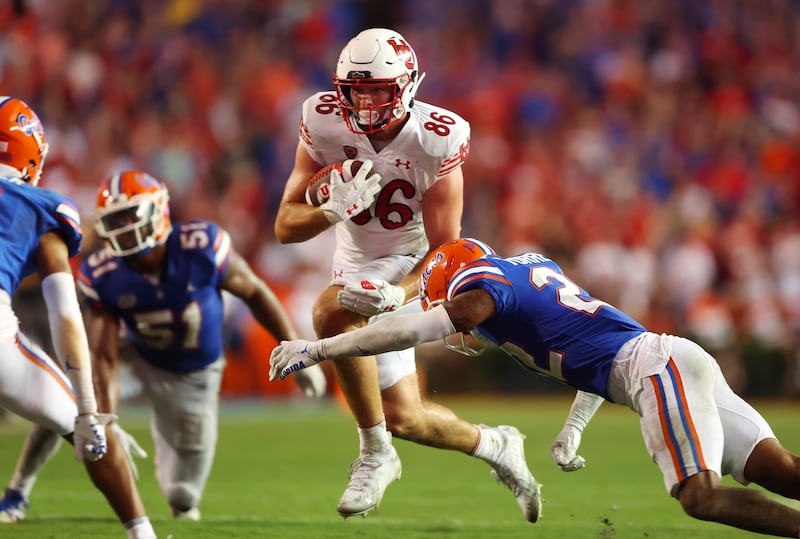 Utah tight end Dalton Kincaid attempts to fend off a tackle from a Florida player.