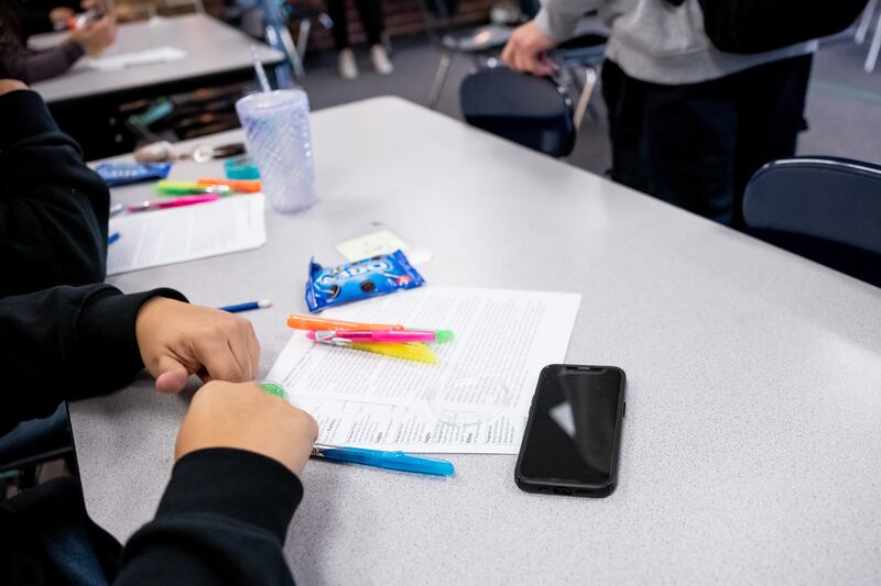 A student has their cellphone out on a table as class begins at Cyprus High School in Magna on Jan. 27, 2023.