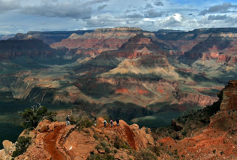 This Feb. 22, 2005 file photo shows the North Rim of the Grand Canyon, background, as tourists hike along the South Rim in Grand Canyon, Arizona. Lower snowfall in recent years at the Grand Canyon’s North Rim is prompting tourism officials to expand the v