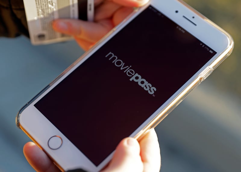 In this Jan. 30, 2018, file photo, Cassie Langdon uses her phone to launch the MoviePass app to see what movies are available at AMC Indianapolis 17 theatre in Indianapolis. MoviePass, a discount service for movie tickets at theaters, is walking back a pl