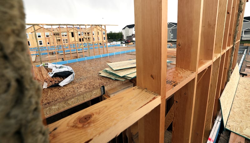 A Lehi town town house construction project is seen through the wood framing of another town town house on May 10, 2021.