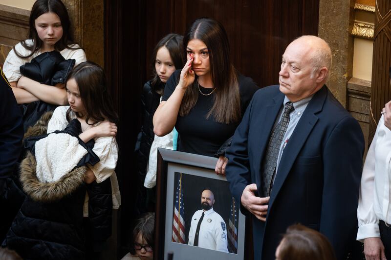 Kate Stockard wipes her eye while holding a photo of her late husband, Weber County Sheriff’s Sgt. Spencer Stockard.