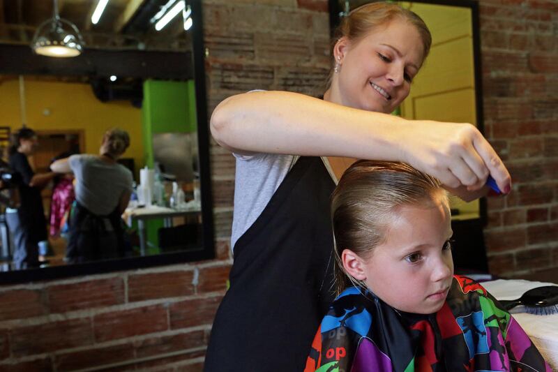 In a Friday, Aug. 28, 2015 photo, Greta Mahoney, 5, of Chesterfield, receives a head lice treatment from technician, Caitlin Bishop, 26, of St. Louis, at Lice Busters, a professional head lice removal company in Richmond Heights, Mo. A new strain of lice