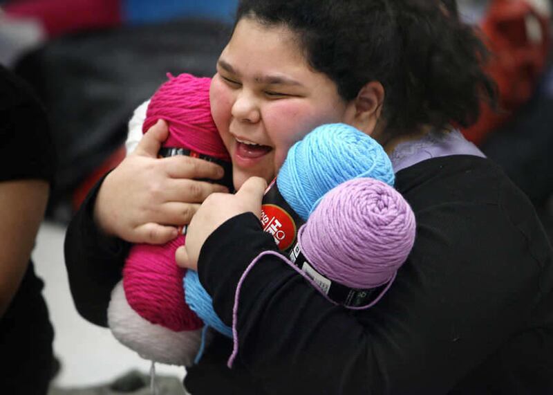 Trina James,12, hugs her new yarn that she is going to use to knit hats for her sister and grandmother at Lincoln Elementary School in Salt Lake City on Thursday, Dec. 15, 2011. Without gifts from the Salt Lake Community and Utah Central Credit Union, man
