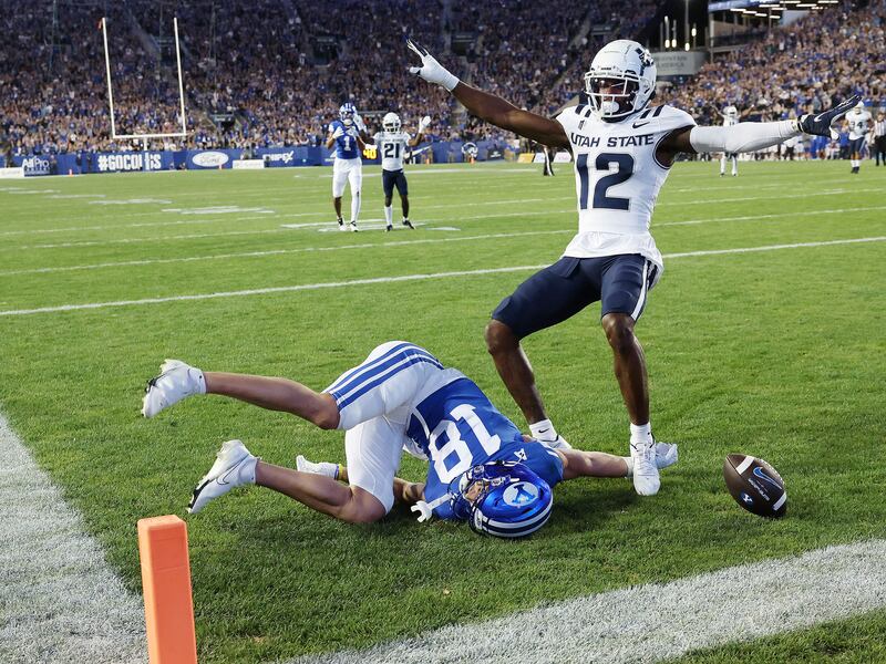 Utah State Aggies cornerback Ajani Carter (wearing white) celebrates the dropped pass by Brigham Young Cougars wide receiver Gunner Romney