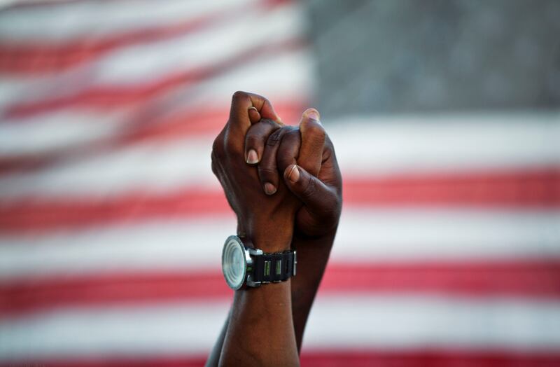 People join hands against the backdrop of an American flag.