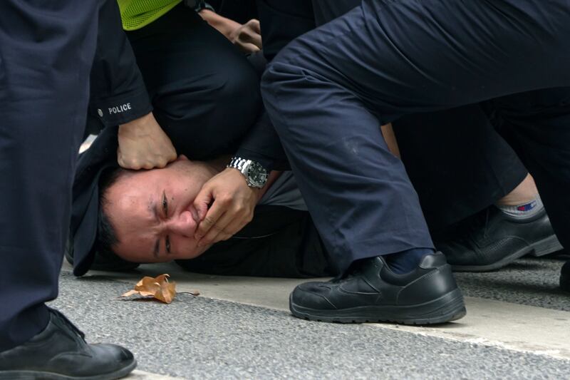 Policemen pin down and arrest a protester during a protest on a street in Shanghai, China, on Sunday, Nov. 27, 2022.