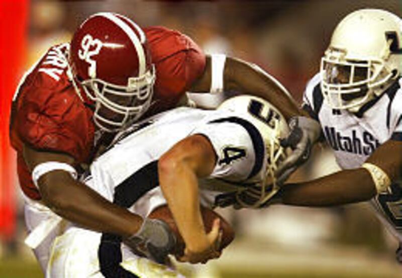 Utah State quarterback Travis Cox (4) is engulfed by Alabama's Wallace Gilberry (92) as running back Chris Forbes attempts a block Saturday.