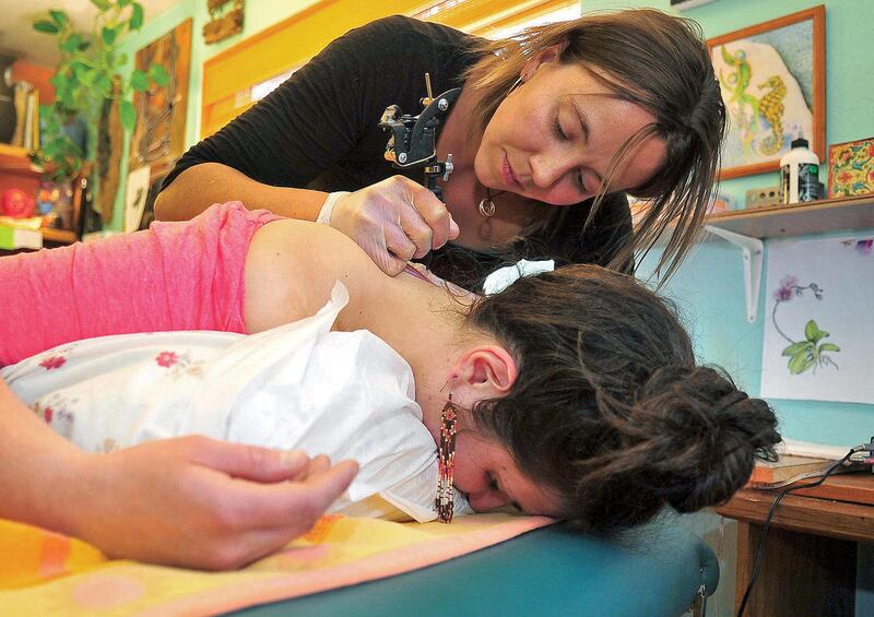 In this photo taken, April 7, 2012, Eva Rupert an apprentice tattoo artist at Port Hole to Soul Tattoo and Piercing gives Rebecca Anlsis her first tattoo Saturday afternoon on Gureley Street in Prescott, Ariz.