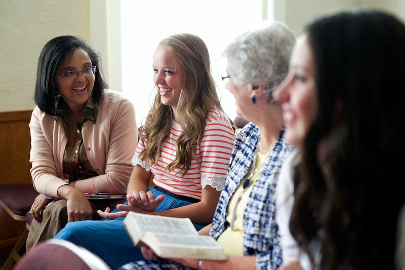 A young woman interacts with older women in a church setting.