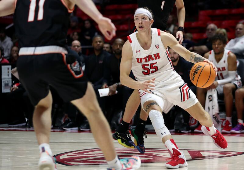 Utah Utes guard Gabe Madsen (wearing white) dribbles the ball